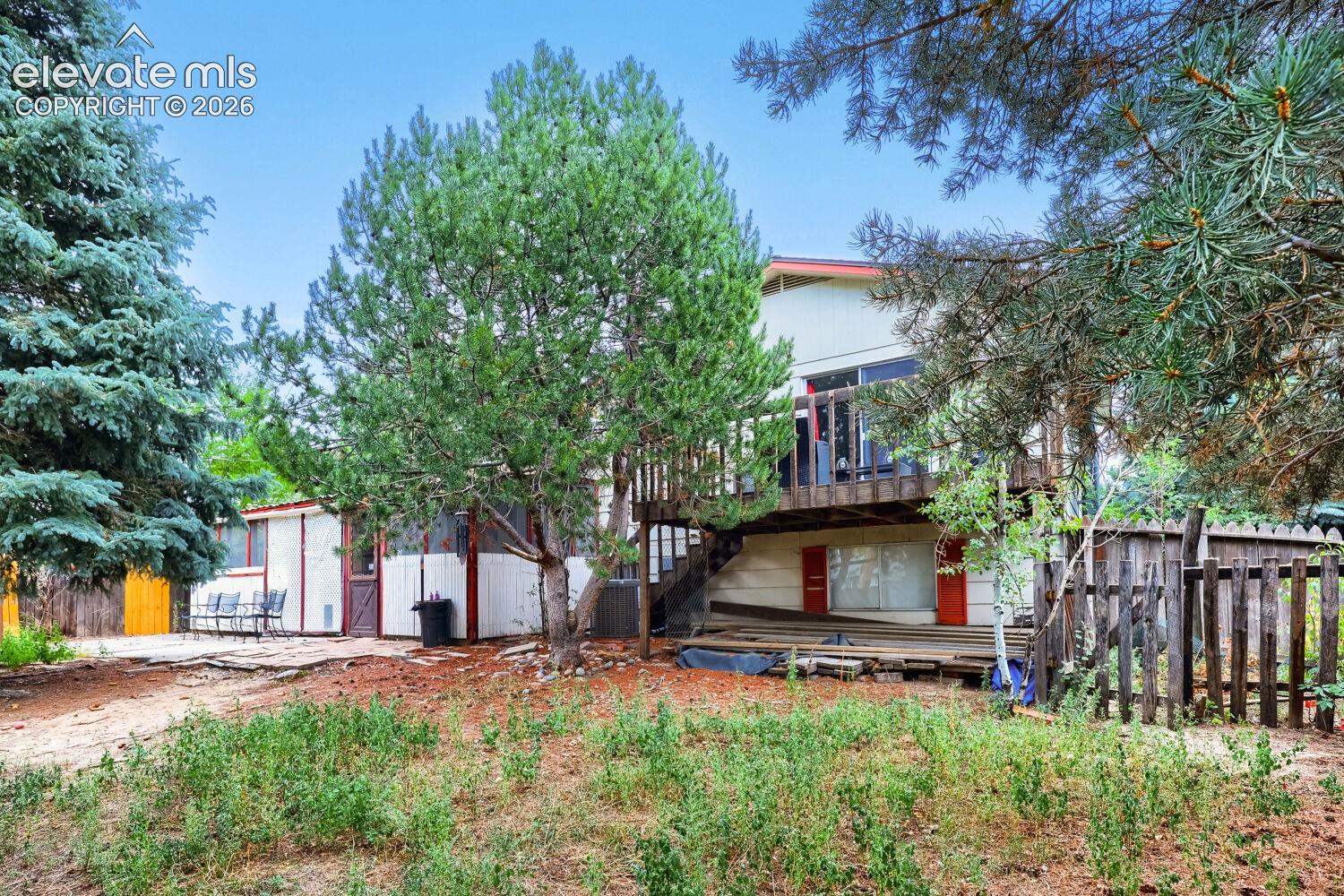 Multi-level exterior with a second-story deck, ground-level patio, and natural wood fencing
