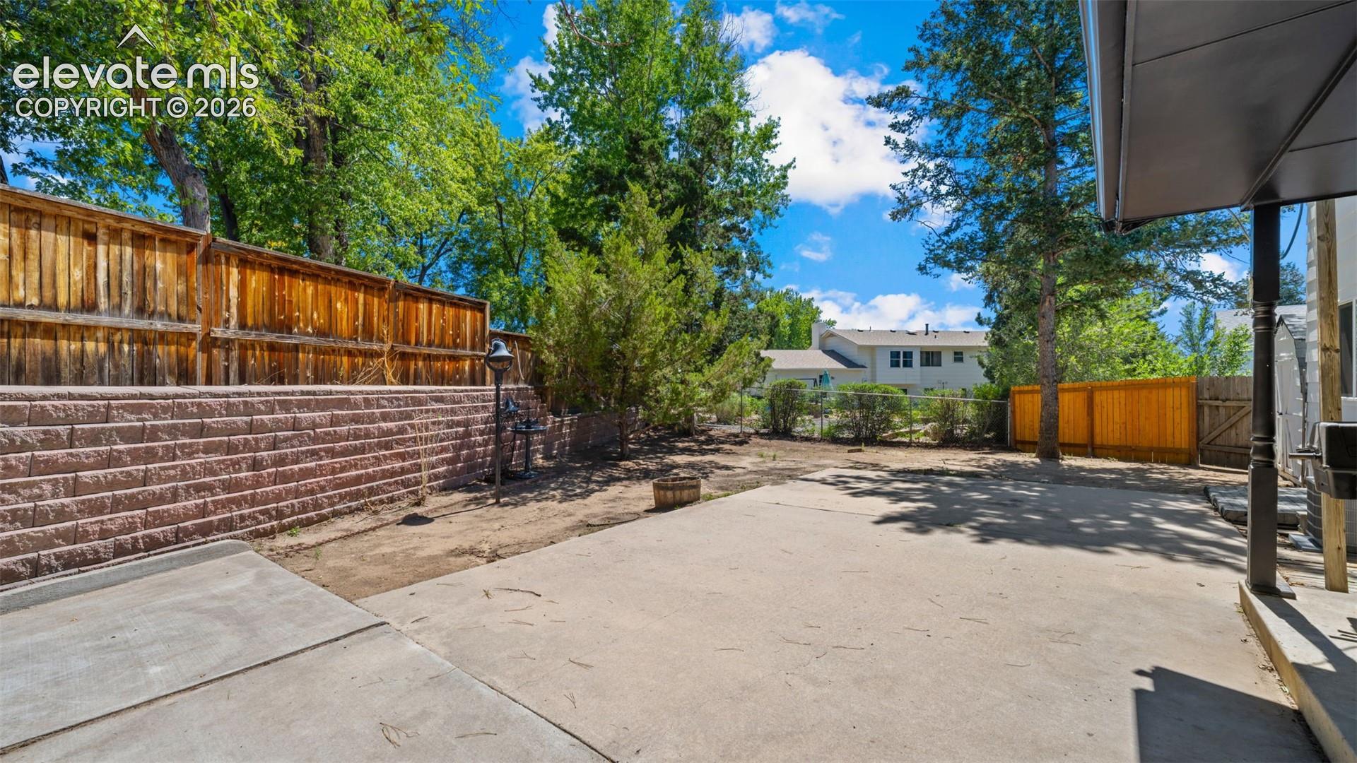 Expansive concrete patio with block retaining wall and wood fencing