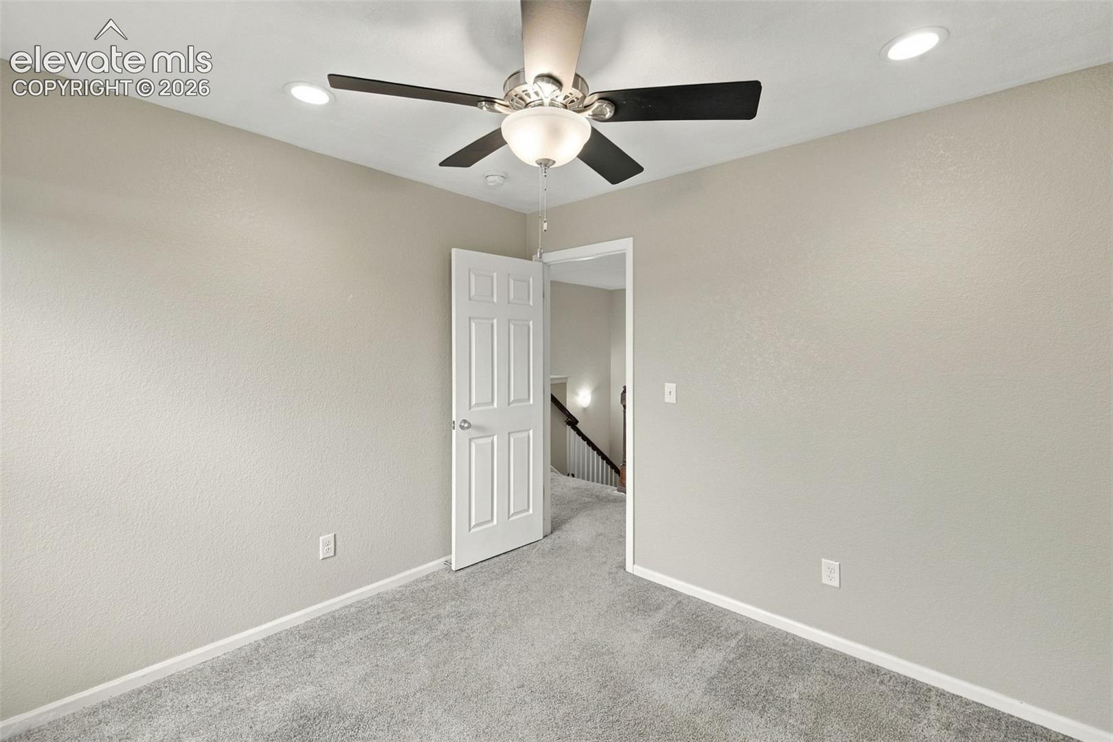 Neutral-toned interior space featuring recessed ceiling lighting, a multi-blade ceiling fan with an integrated light fixture, and wall-to-wall carpeting