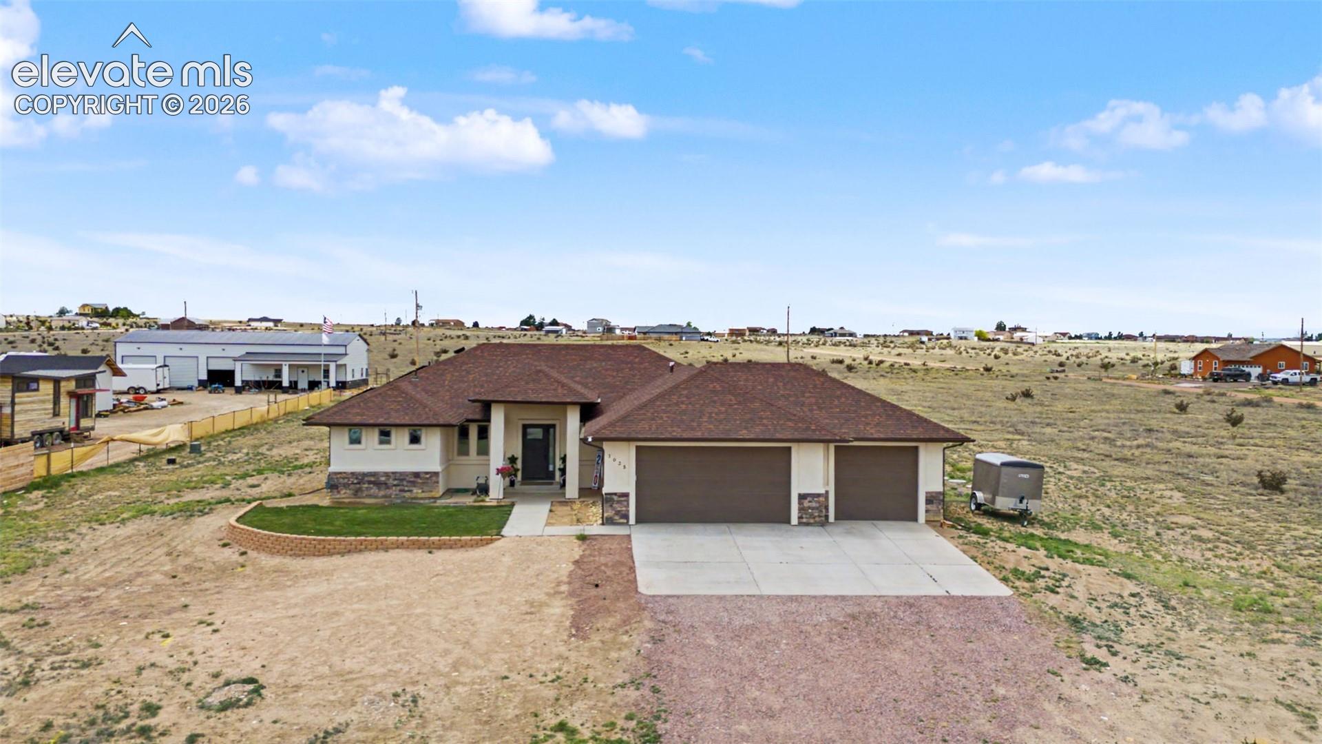 Contemporary ranch-style exterior featuring a two-car garage, stone accent siding, and a covered entryway