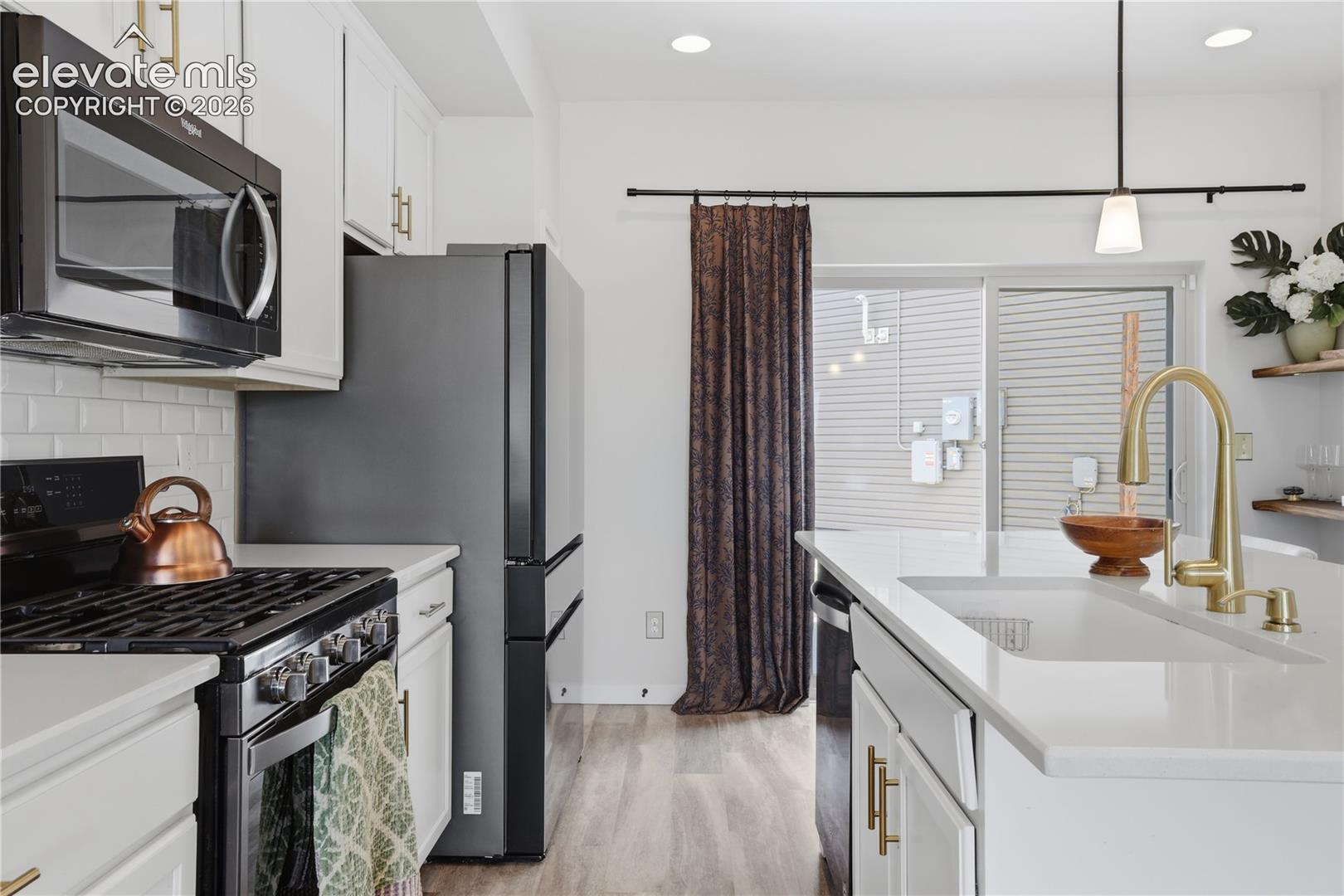 Contemporary kitchen featuring white cabinetry, a white subway tile backsplash, and wood-finish flooring