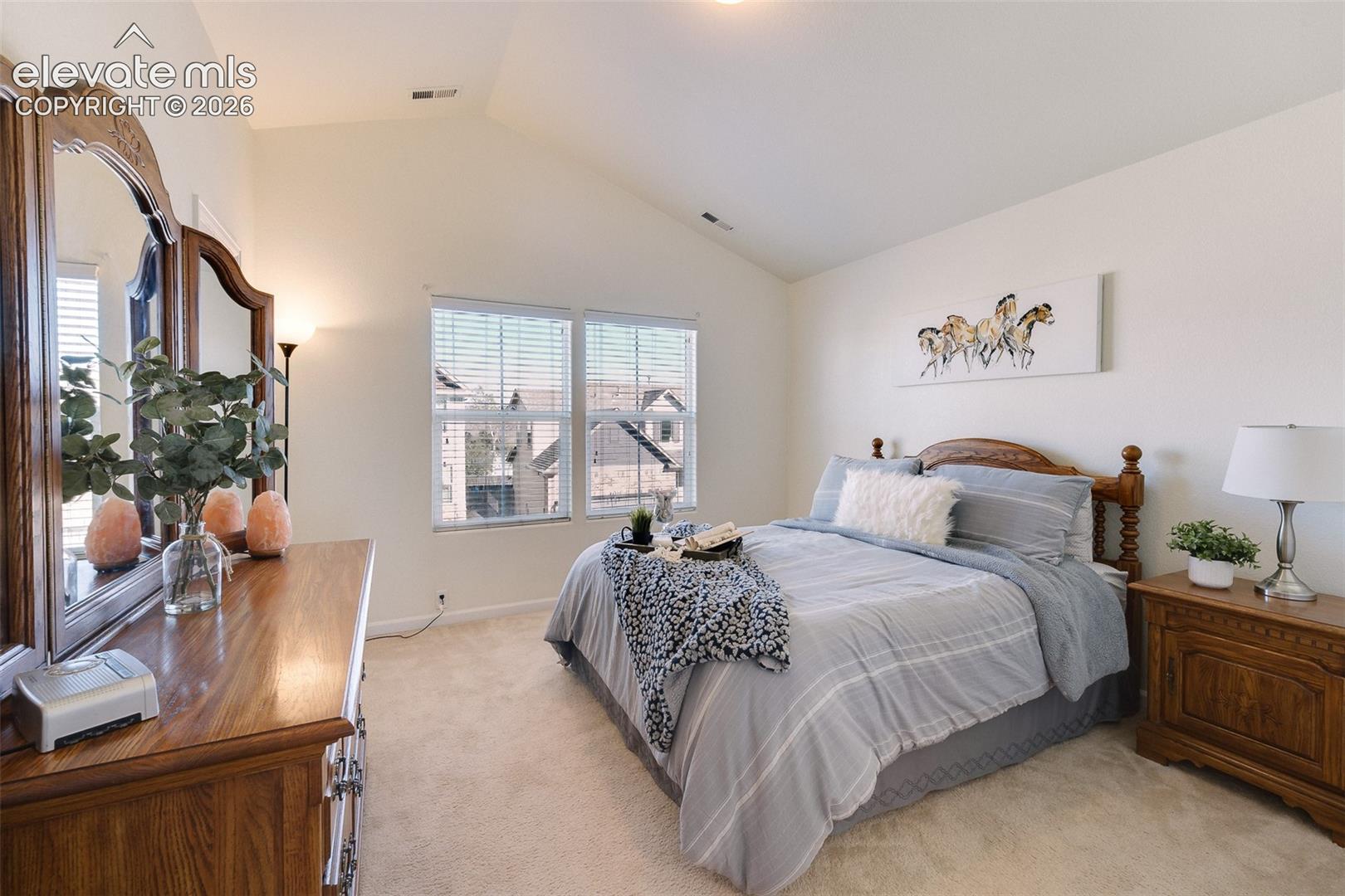 Vaulted ceilings, neutral wall color, carpeted flooring, and a pair of windows with blinds