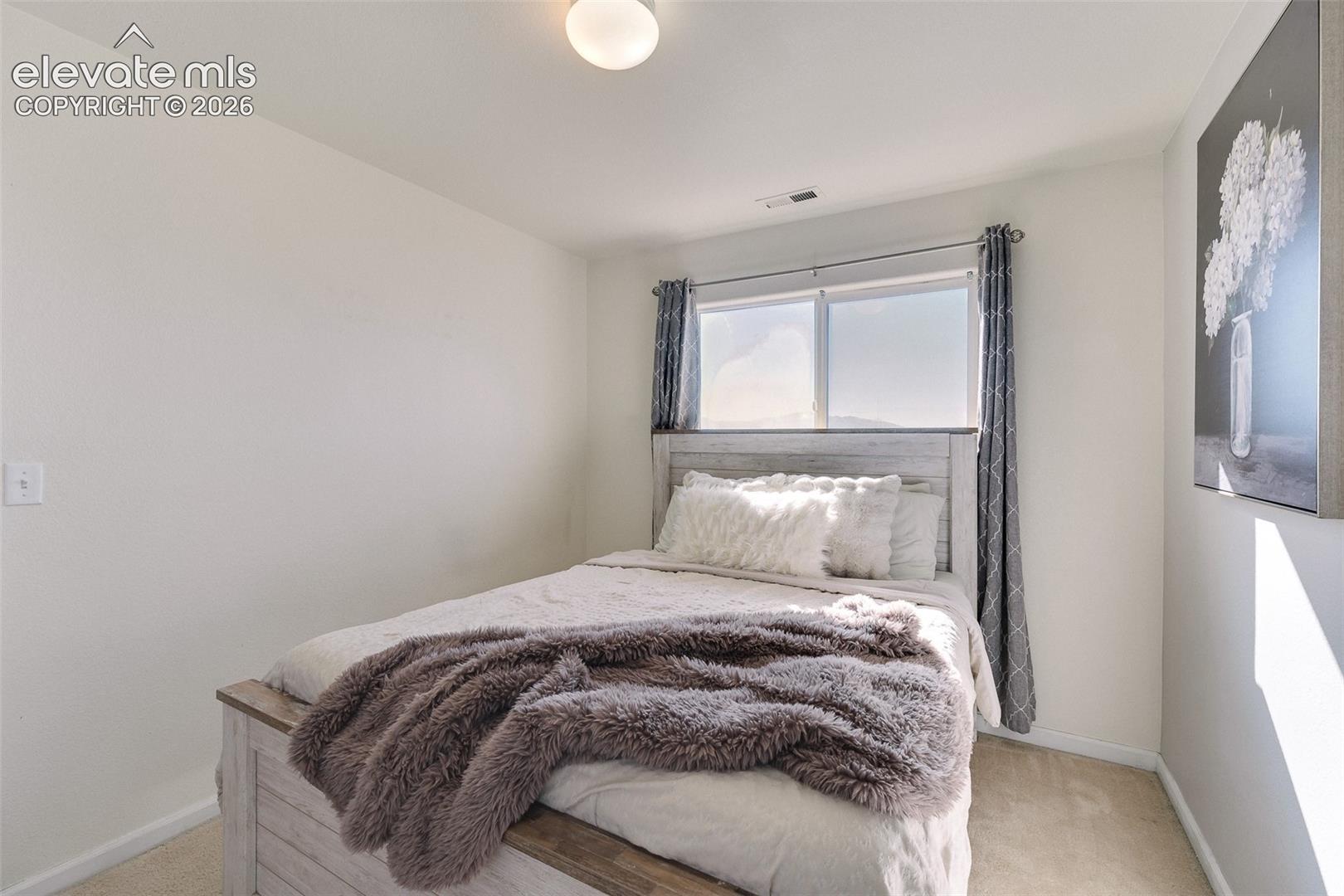 Bright interior space with light-toned walls, a window offering natural light, and neutral-toned carpeting