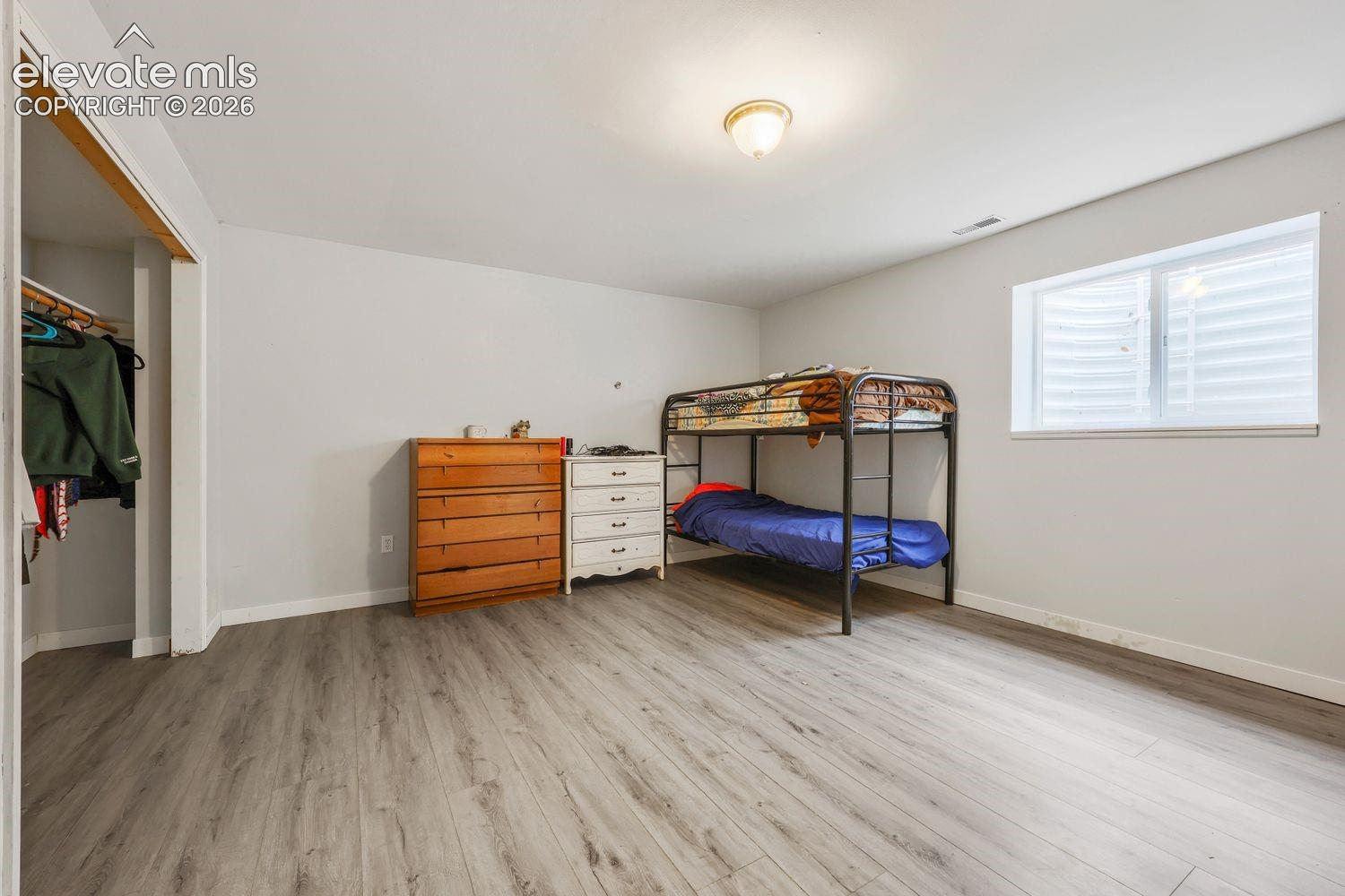 Spacious room featuring wood-finish flooring, a functional window, and an open closet