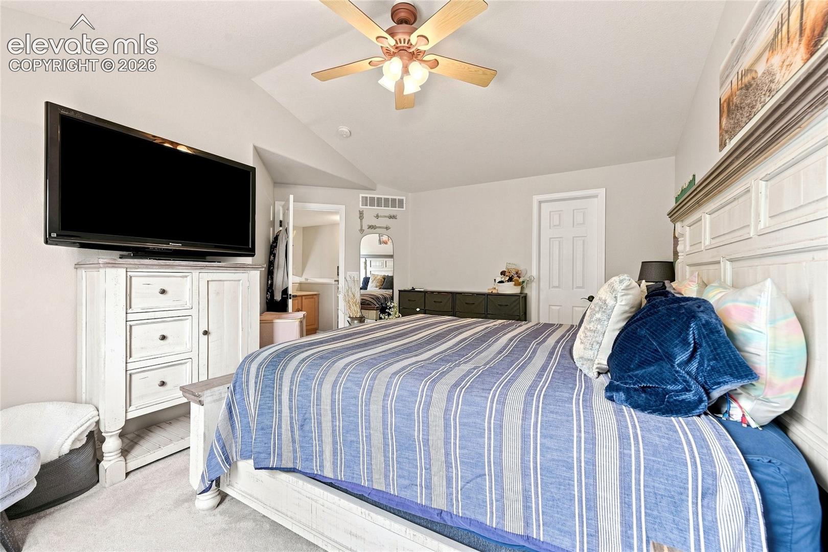 Vaulted ceiling with a multi-blade ceiling fan and neutral wall finish