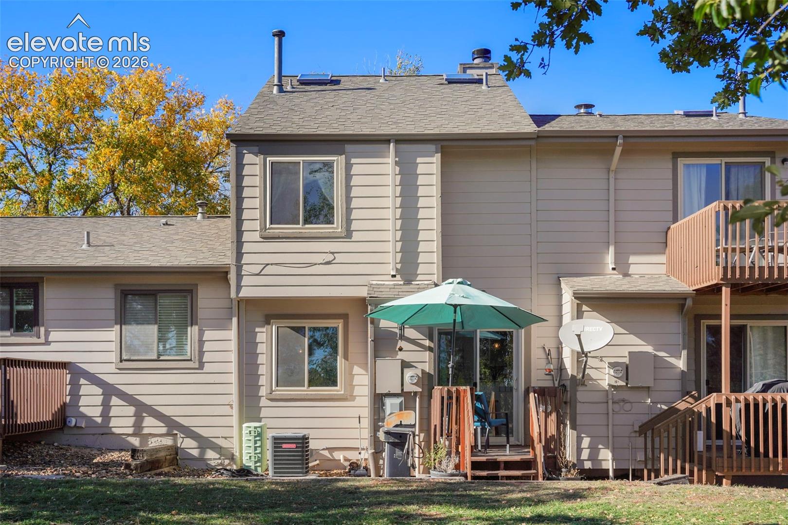 Multi-level exterior featuring horizontal siding, a second-story wooden deck, a ground-level wood patio, and multiple sliding glass doors