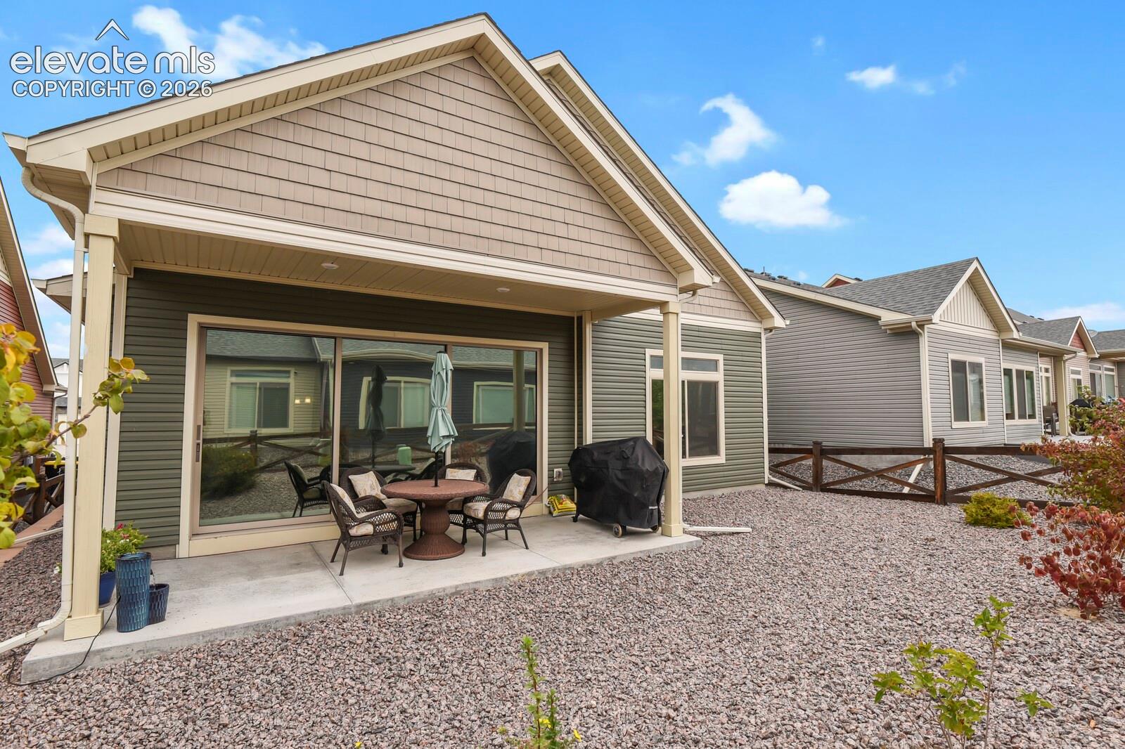 REAR SLIDING DOOR IS TINTED AND REFLECTIVE FOR PRIVACY INSIDE, Covered with recessed lighting and exterior siding featuring low maintenance landscaping, complemented by decorative cross-buck wood fencing and rock landscaping