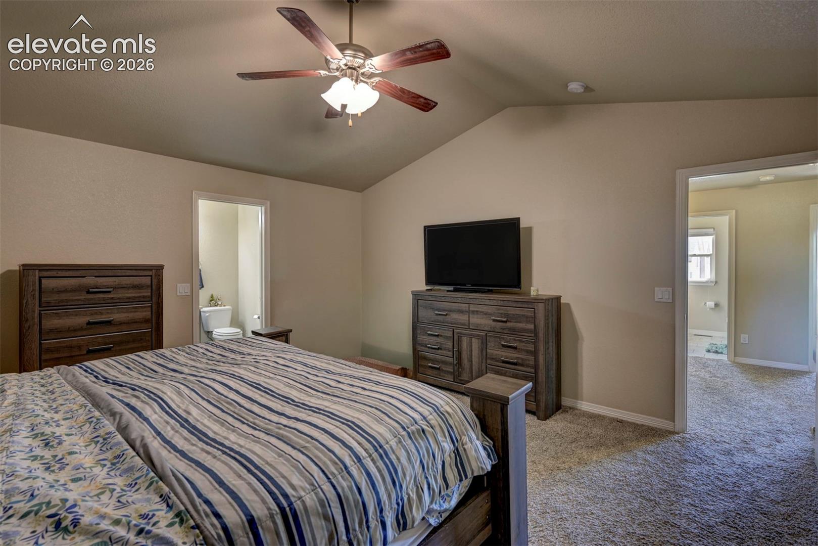 Vaulted ceiling with a ceiling fan, neutral wall color, and carpet flooring