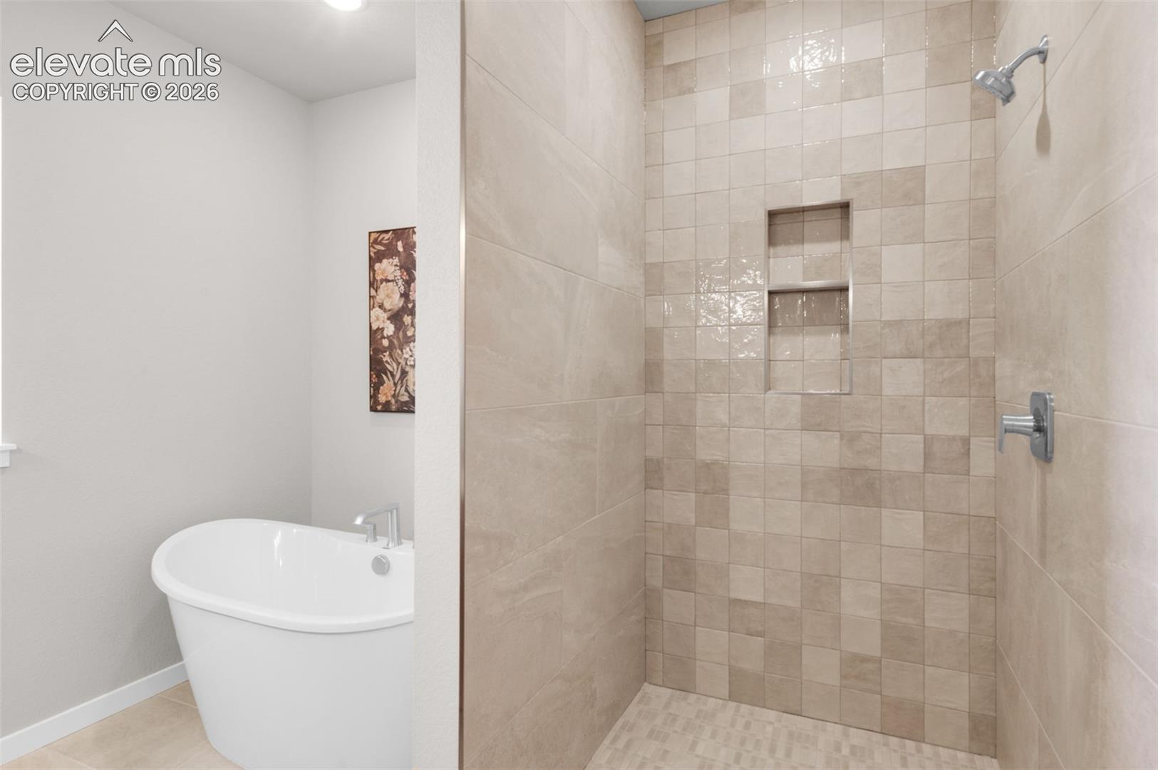 Freestanding soaking tub, tiled walk-in shower, dual shower niches, chrome shower fixtures, and light-toned tile flooring