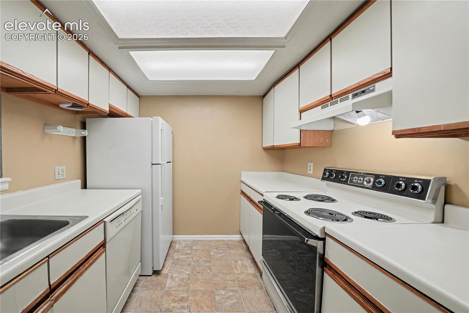 Kitchen with wood cabinetry and white appliances