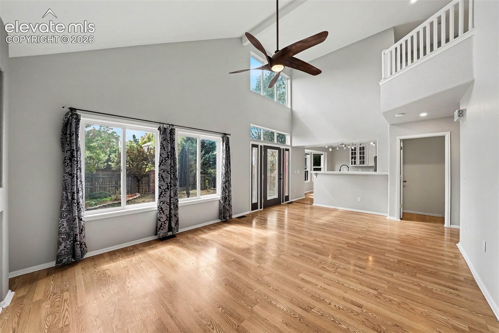 Vaulted ceilings, wood-finish flooring, and multiple windows with transoms