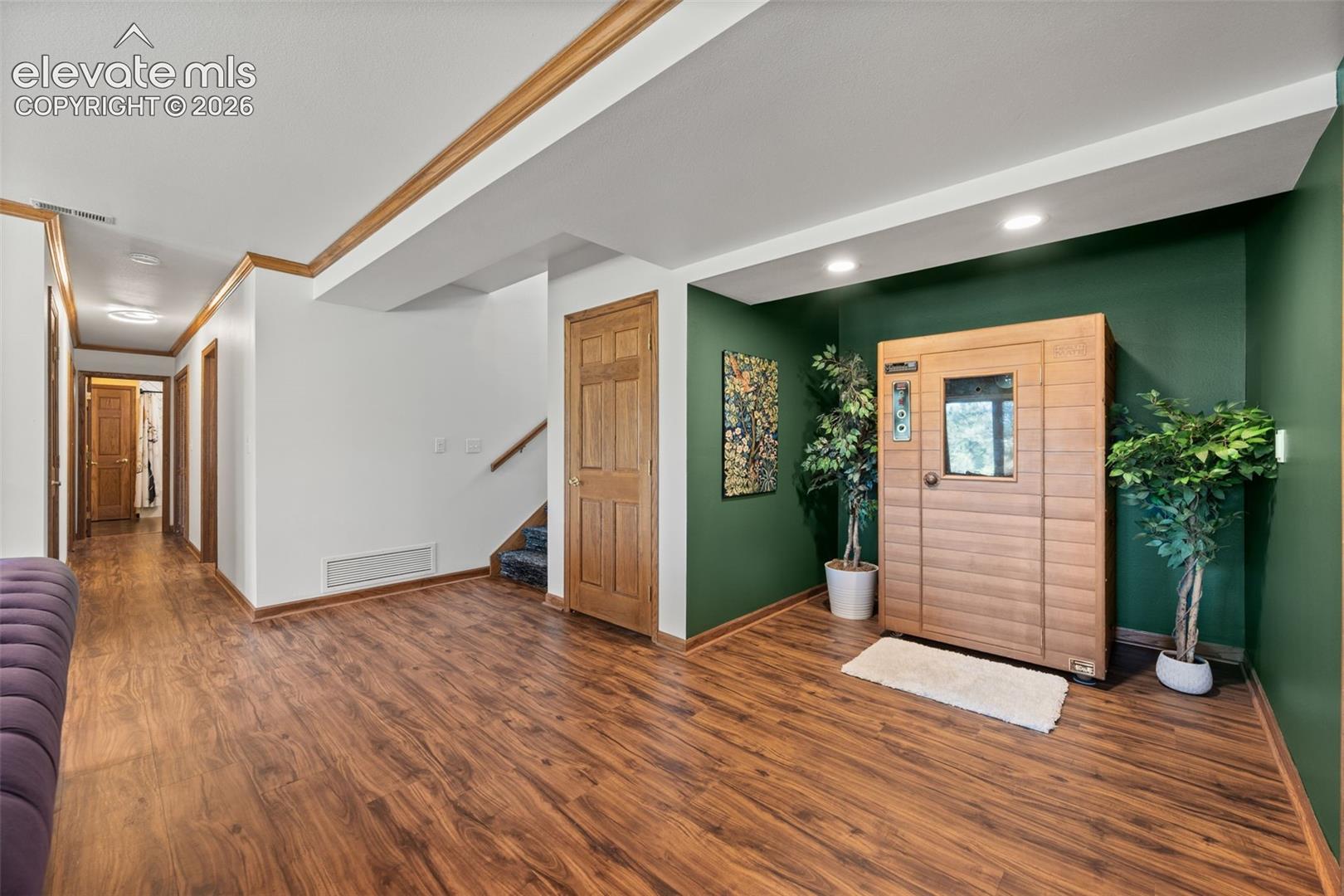 Lower level area featuring a built-in sauna, wood-finish flooring, recessed lighting, and rich emerald accent wall