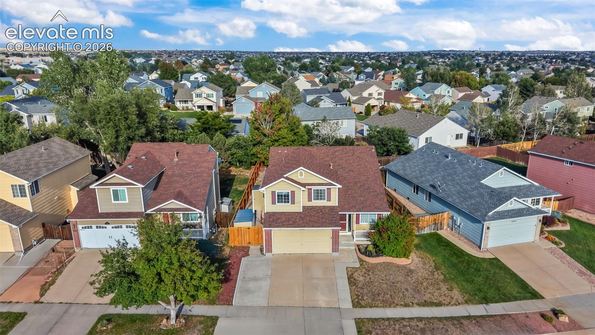 Two-story residence featuring a two-car garage, front landscaping, and a fenced backyard