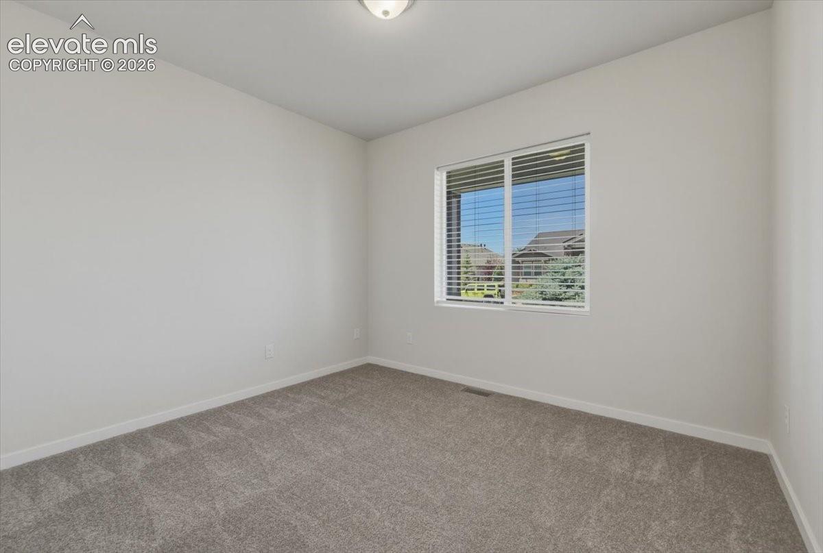 Carpeted room with neutral walls, featuring a window with white blinds