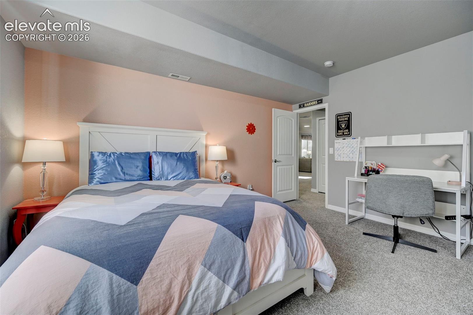 Carpeted room featuring a white paneled headboard and a dedicated workspace