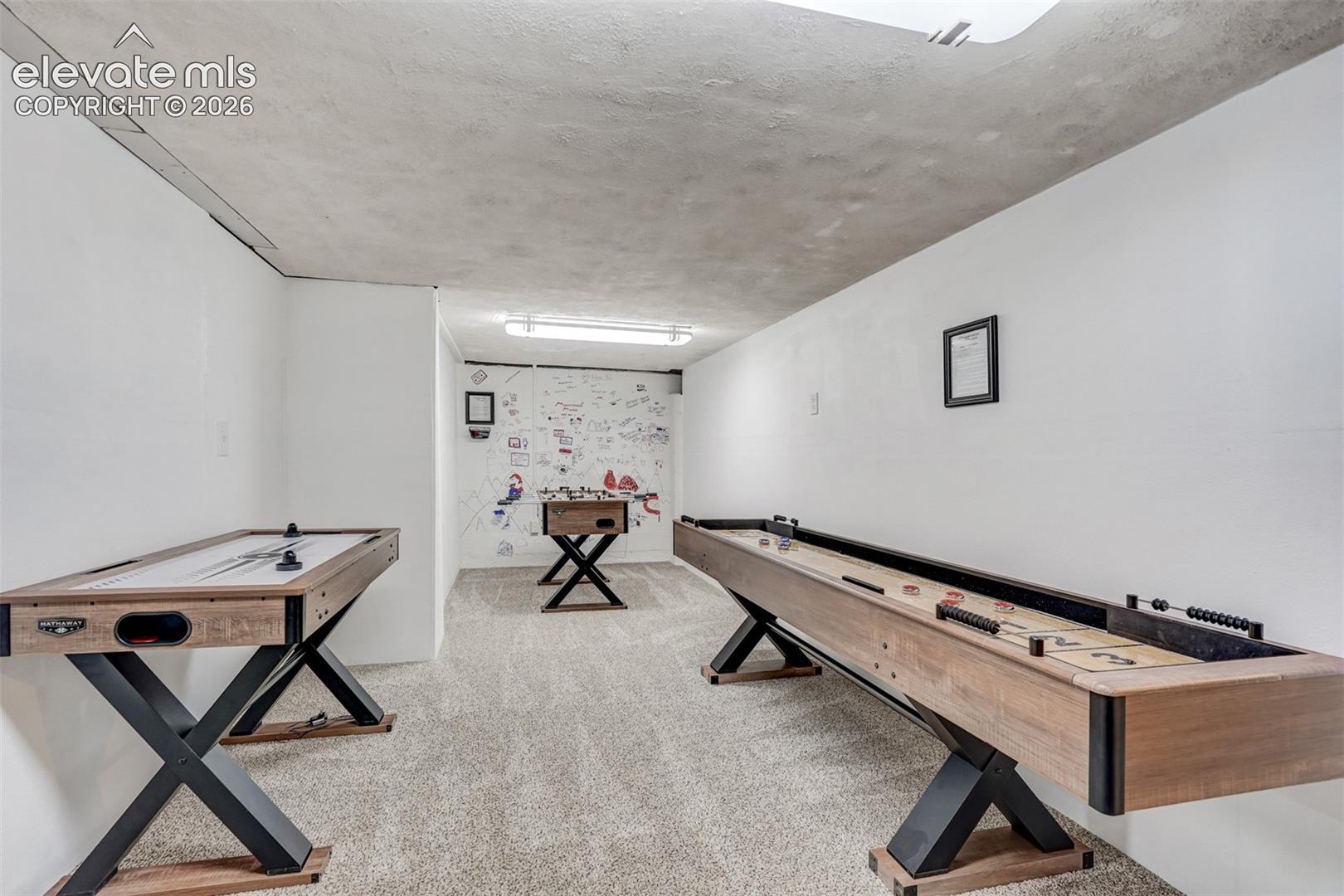 Carpeted flooring throughout a recreation space with white walls and a textured ceiling