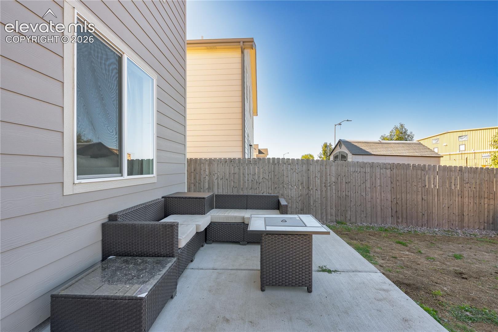 Concrete patio featuring horizontal lap siding, a sliding window with a screen, and a privacy wood fence
