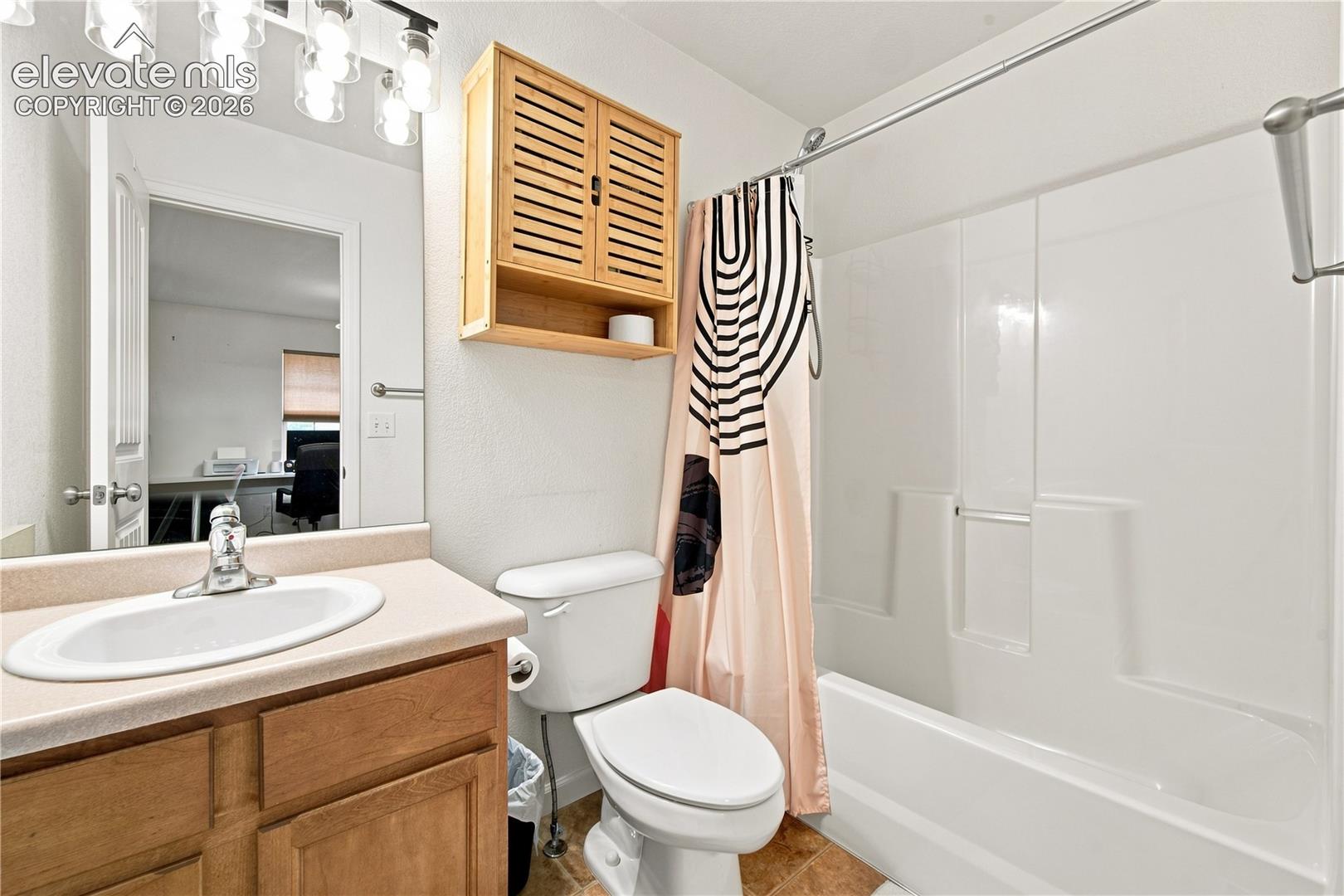 Vanity with an oval basin sink, a light-toned countertop, and a wood-finish cabinet