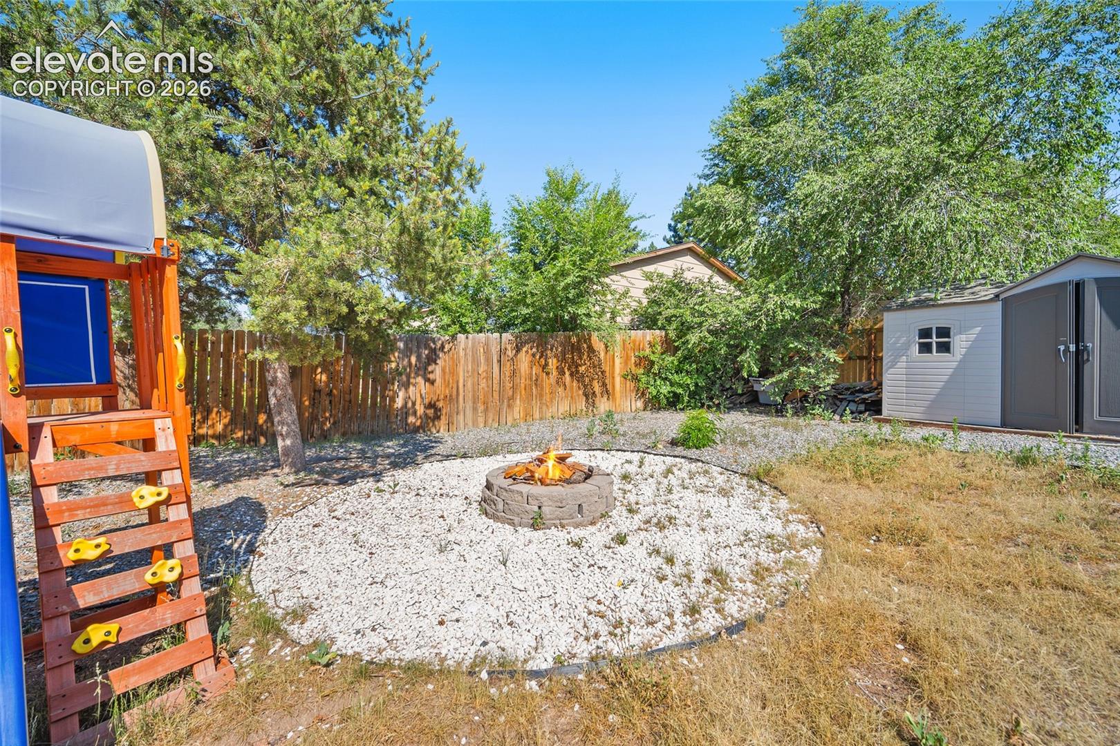 Backyard with fire pit, play area, and storage shed.