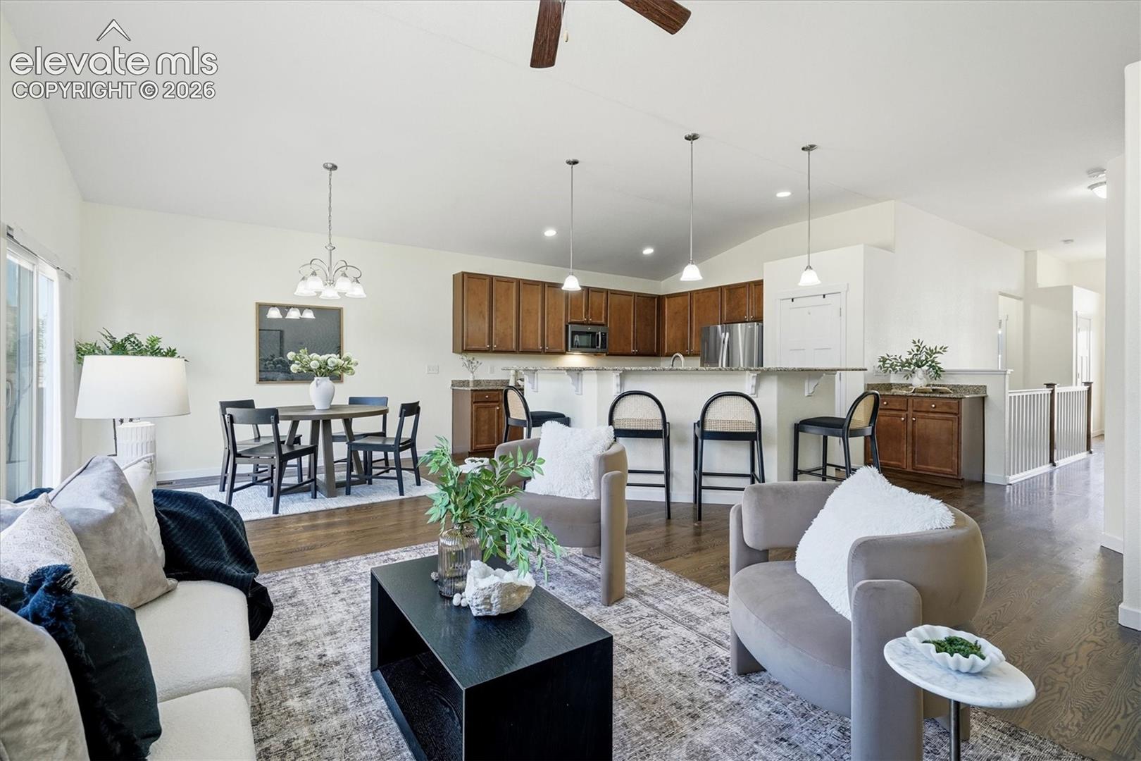 Vaulted ceilings, wood-finish flooring, recessed lighting, built-in kitchen cabinetry, and a kitchen island with pendant lighting