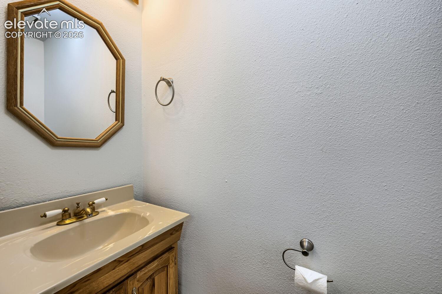Wood-finish vanity with an integrated sink and brass-tone faucet