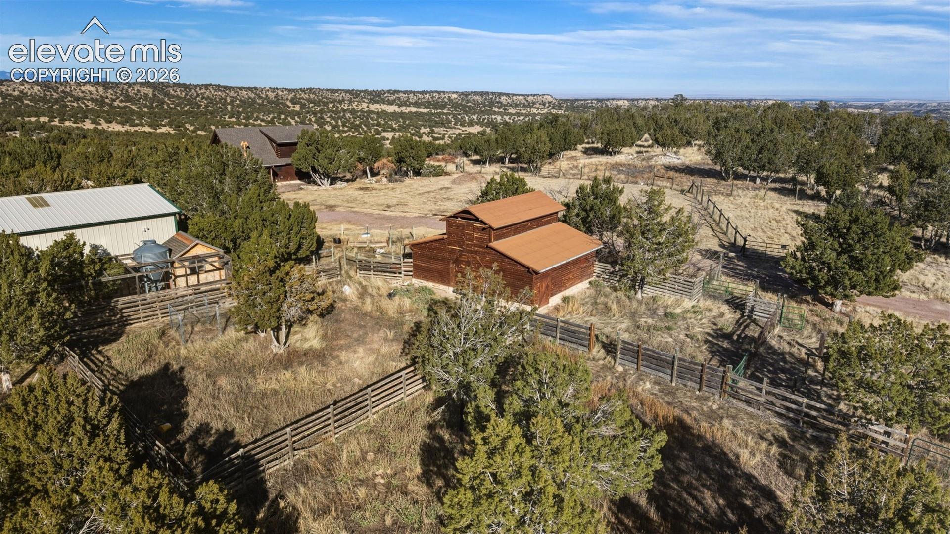 Rural landscape with multiple structures, natural vegetation, and extensive fencing