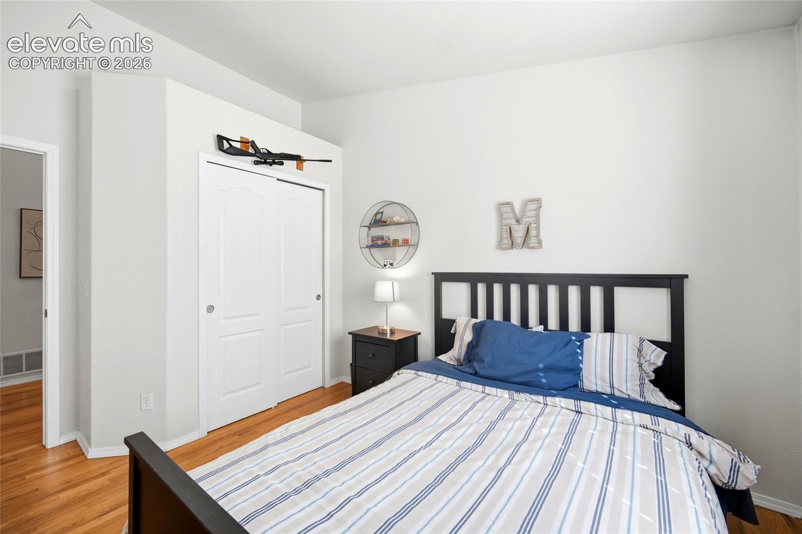 Hardwood flooring, painted white walls, white sliding closet doors, and an open doorway