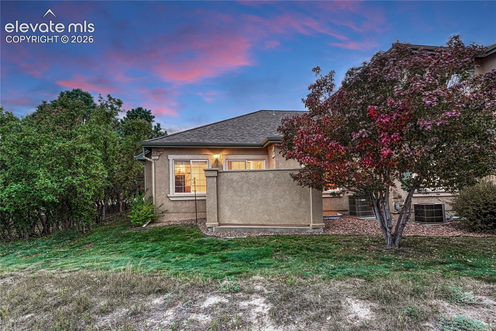 Evening twilight view displaying the home's private patio enclosure and peaceful tree-lined surroundings
