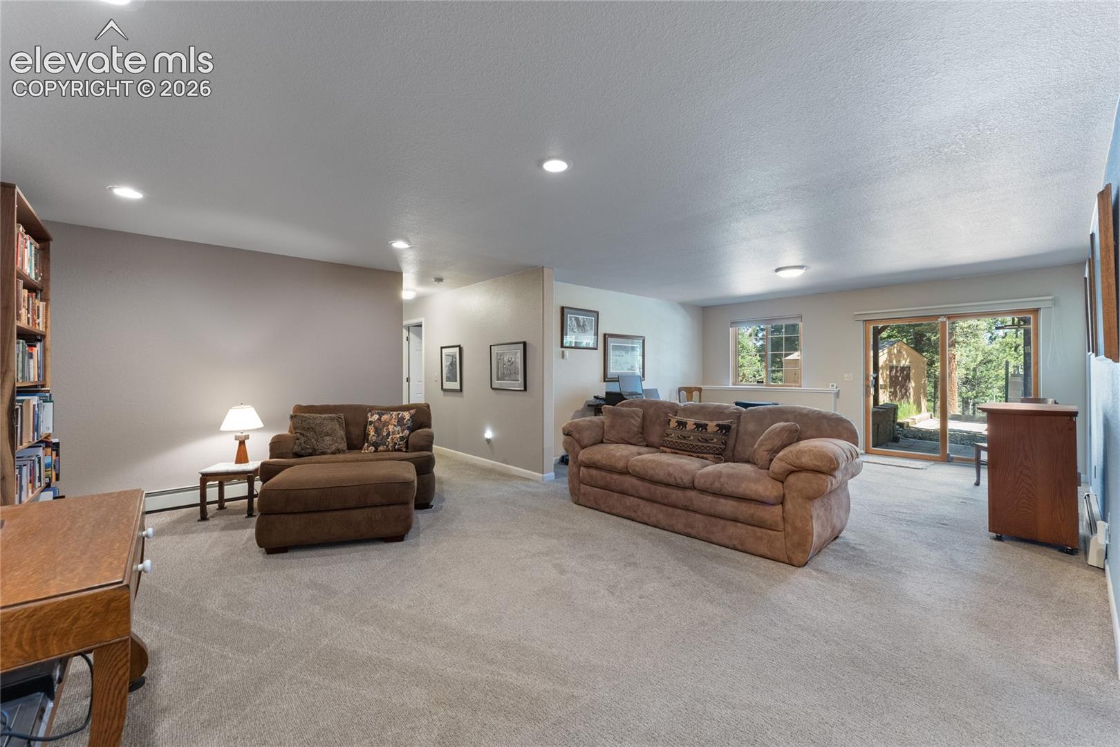 Spacious interior featuring neutral carpet flooring, recessed lighting, and a built-in bookshelf