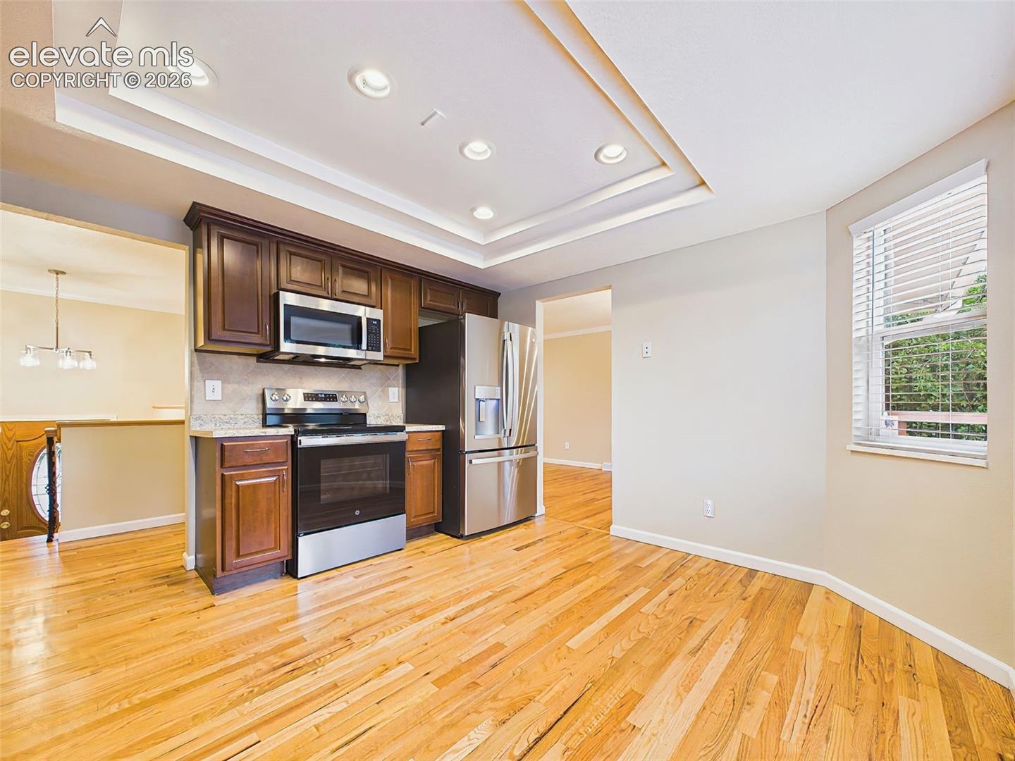 Bright eat-in kitchen featuring rich wood cabinetry, durable laminate countertops, stainless steel appliances, recessed lighting, and beautiful hardwood floors.