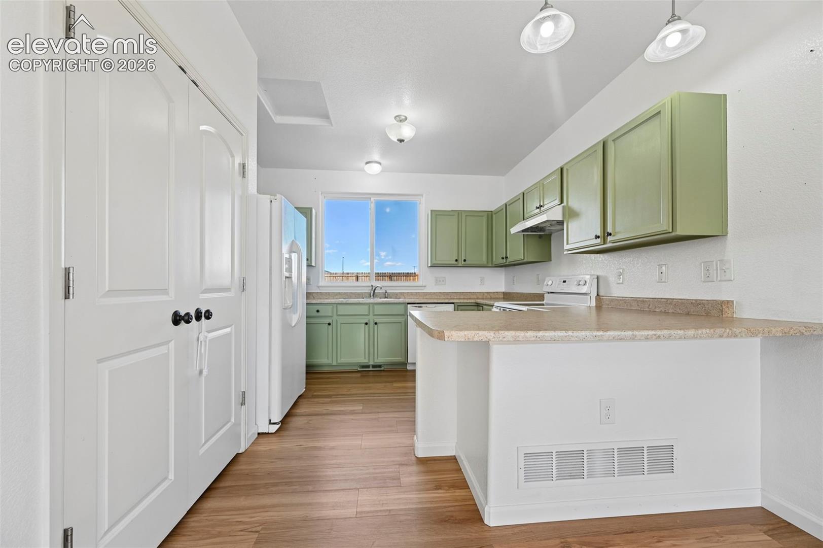 Kitchen featuring wood-finish flooring, solid-surface countertops, custom-painted cabinetry, dual pendant lighting, and a windowed exterior exposure
