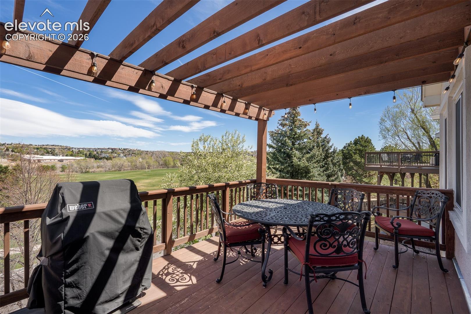 Expansive outdoor upper deck featuring a wood pergola and string lighting.  Stunning view of Cottonwood park.
