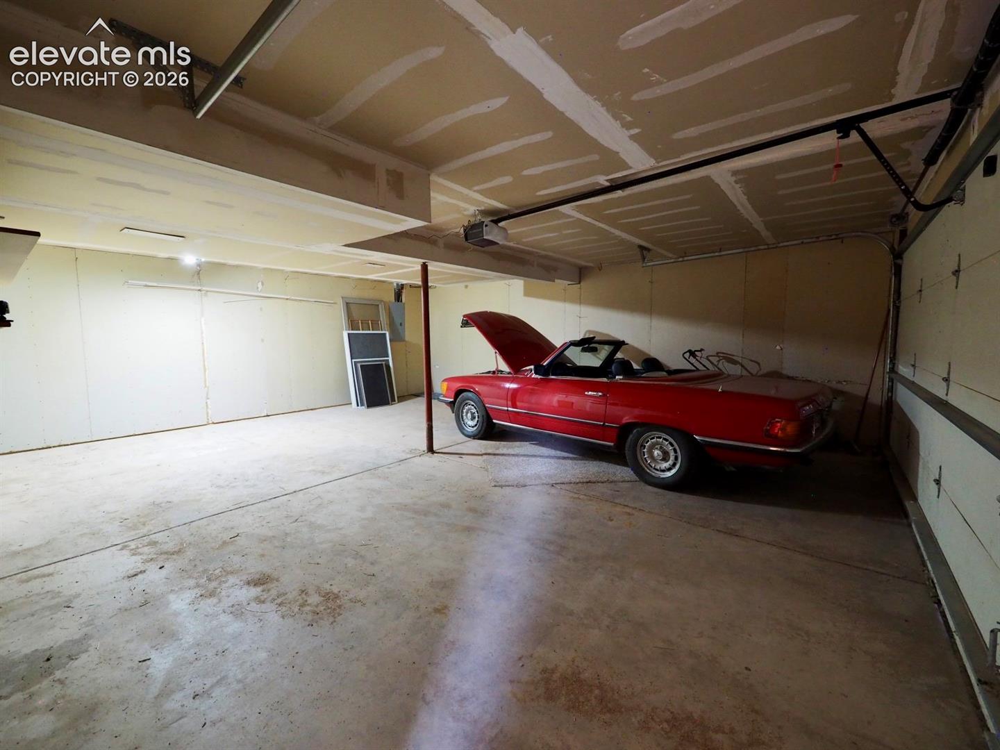 Multi-car garage featuring a concrete floor, high ceilings, and an automated overhead door system
