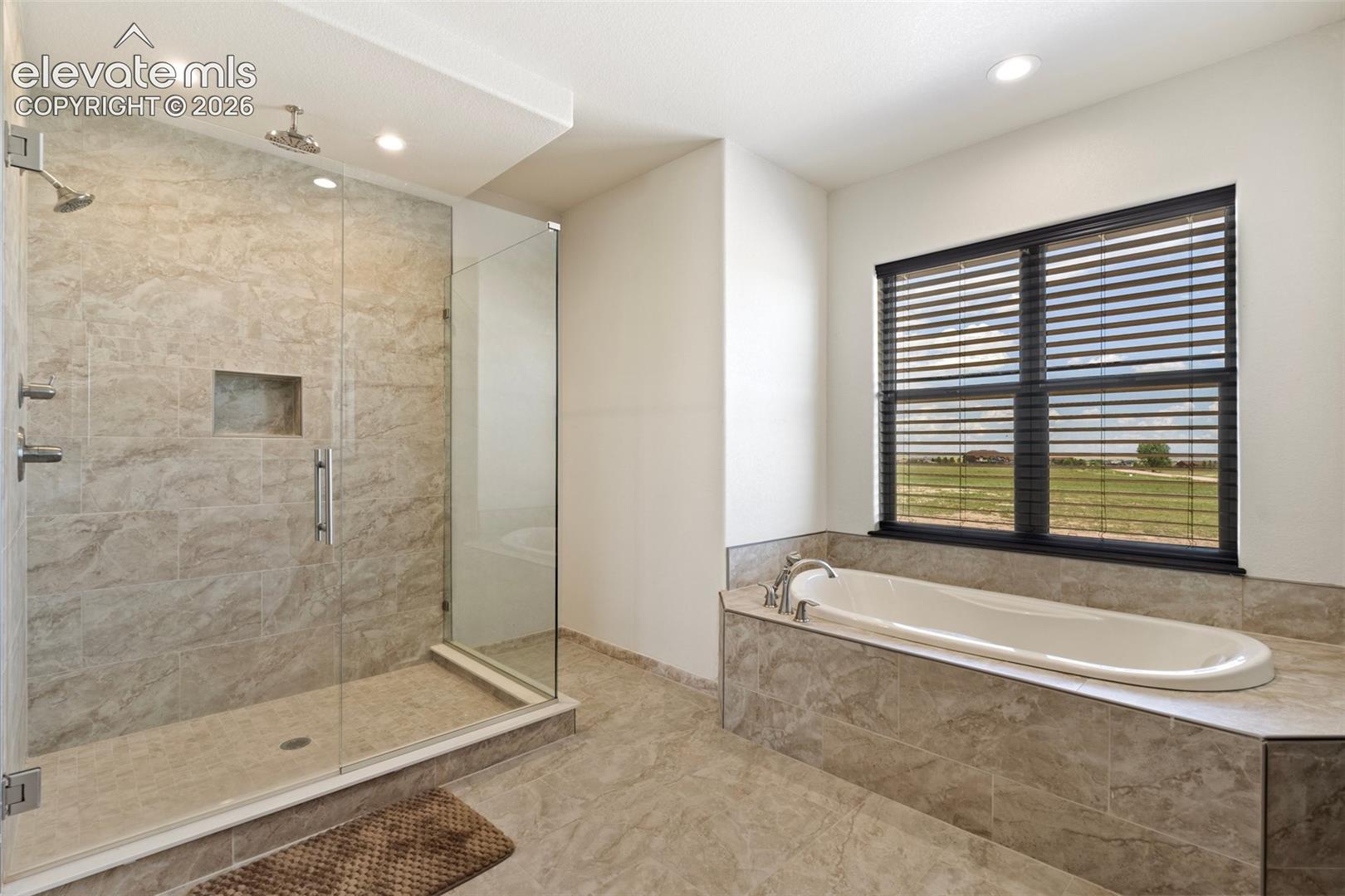 Walk-in shower with full glass enclosure and built-in niche and relaxing soaking tub