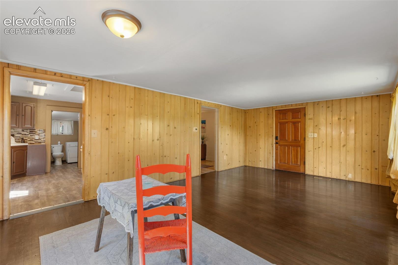 Spacious room featuring wood-panel walls and dark wood-finish flooring