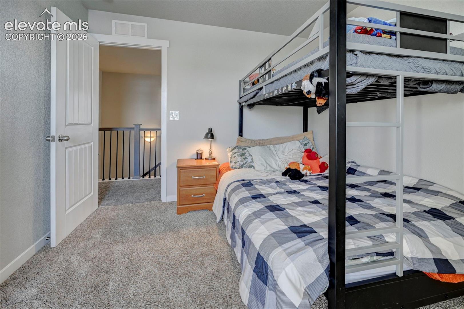 Interior space featuring neutral wall tones, textured carpeting, and a three-panel interior door with brushed metal hardware