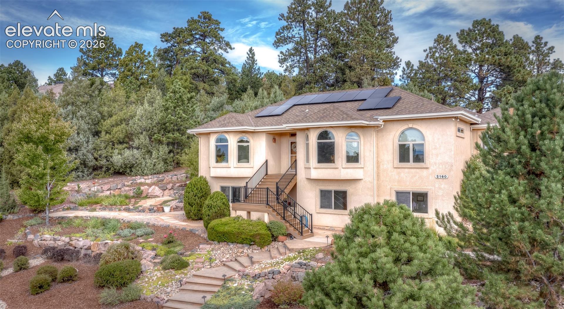 Stucco exterior with multiple arched windows and solar panels