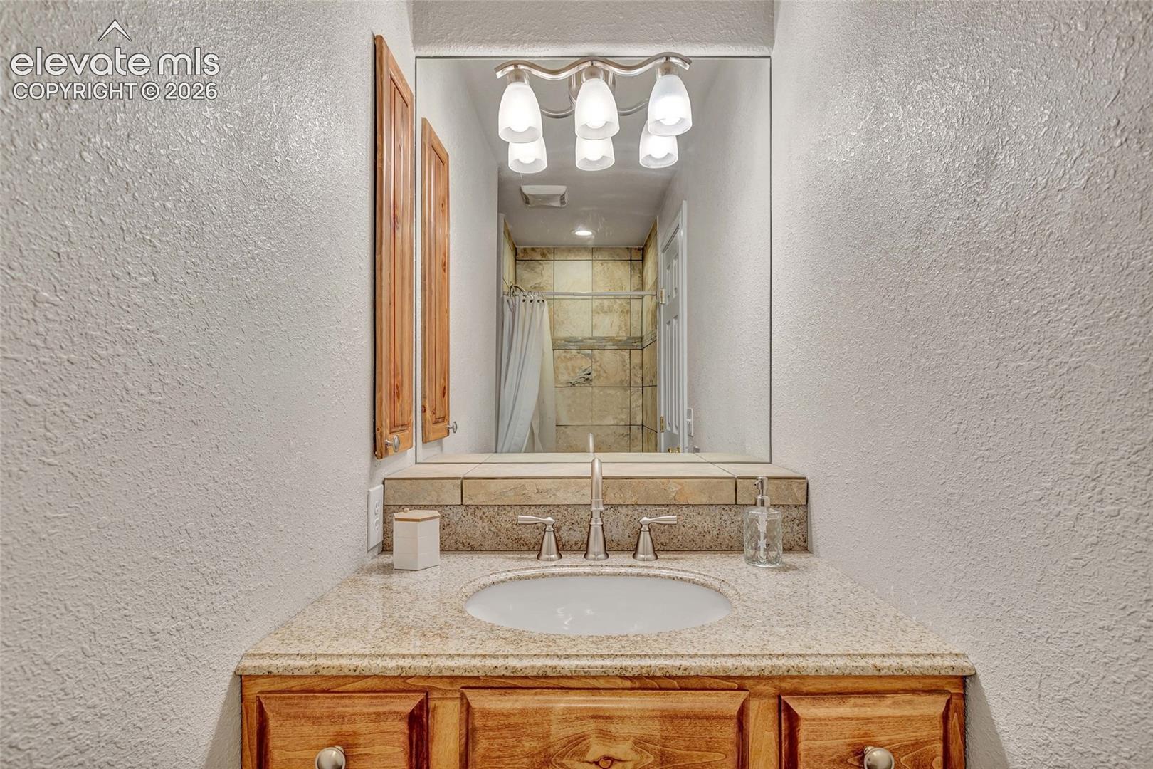 Vanity featuring a built-in sink, granite countertop, and wood-finish cabinetry