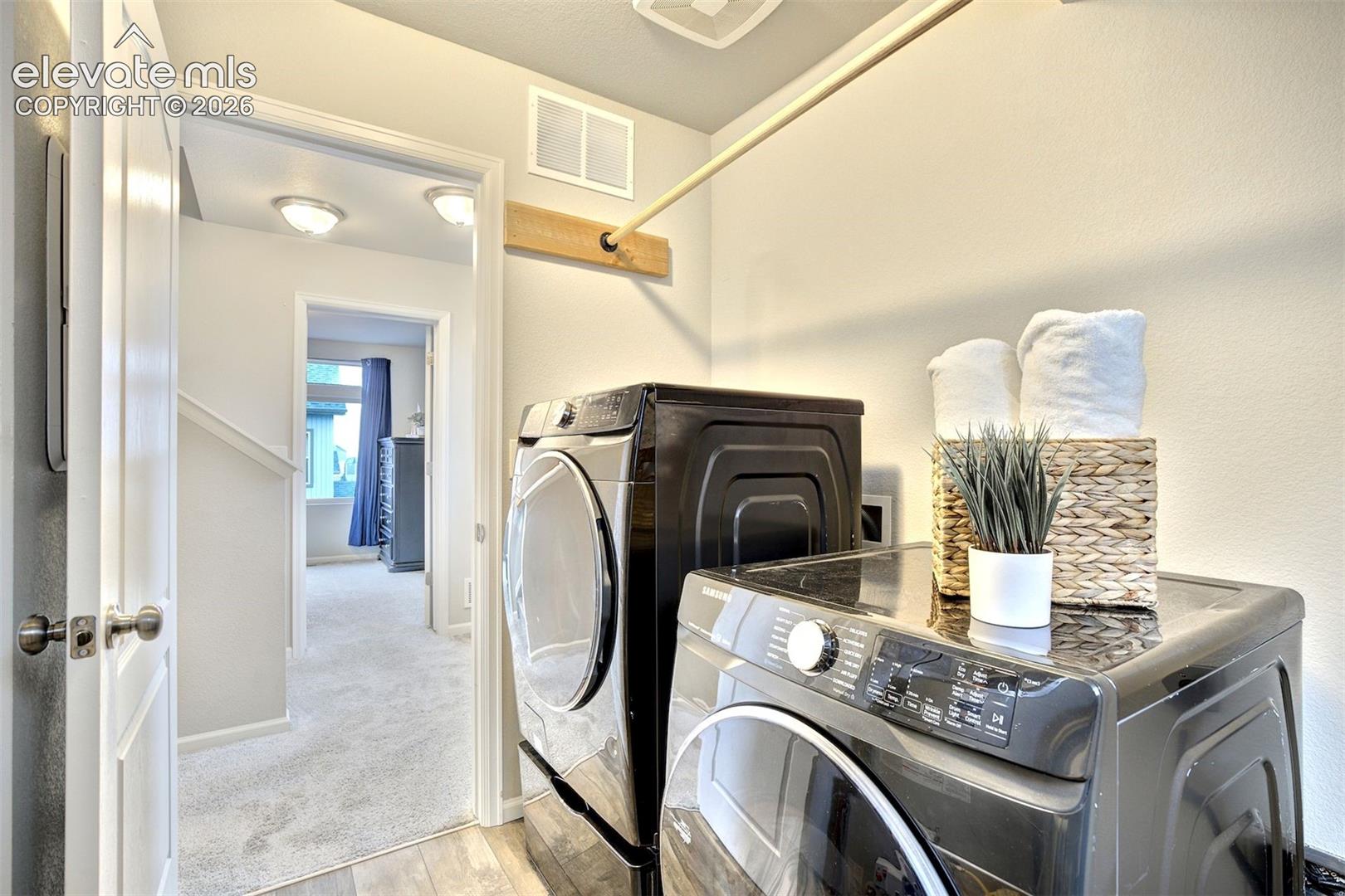 Laundry area featuring hard-surface flooring and a wall-mounted hanging rod