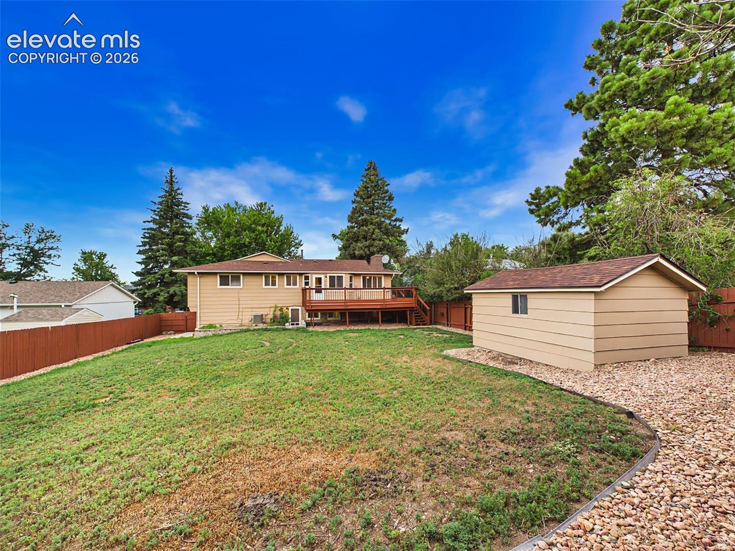 Expansive, fully fenced backyard with a large lawn, mature trees, and a spacious storage shed, offering plenty of room for outdoor enjoyment.