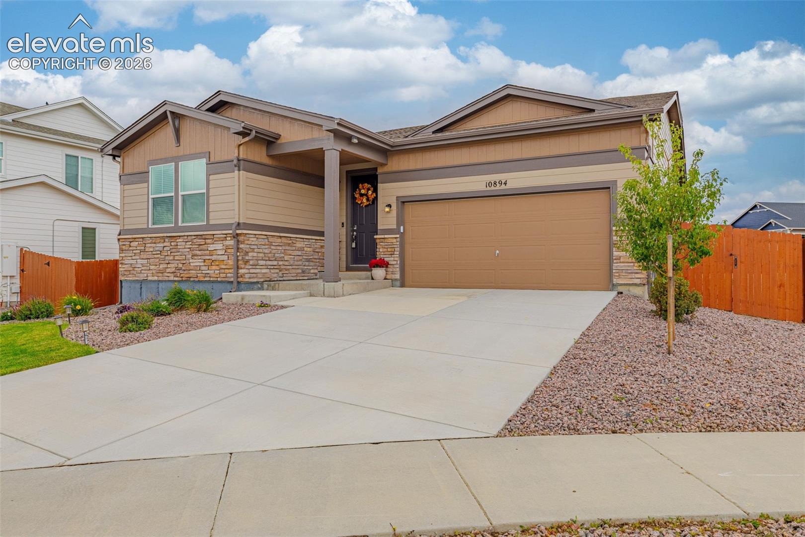Modern exterior featuring stone veneer accents, an attached garage, a covered entry, a concrete driveway, and low-maintenance landscaping