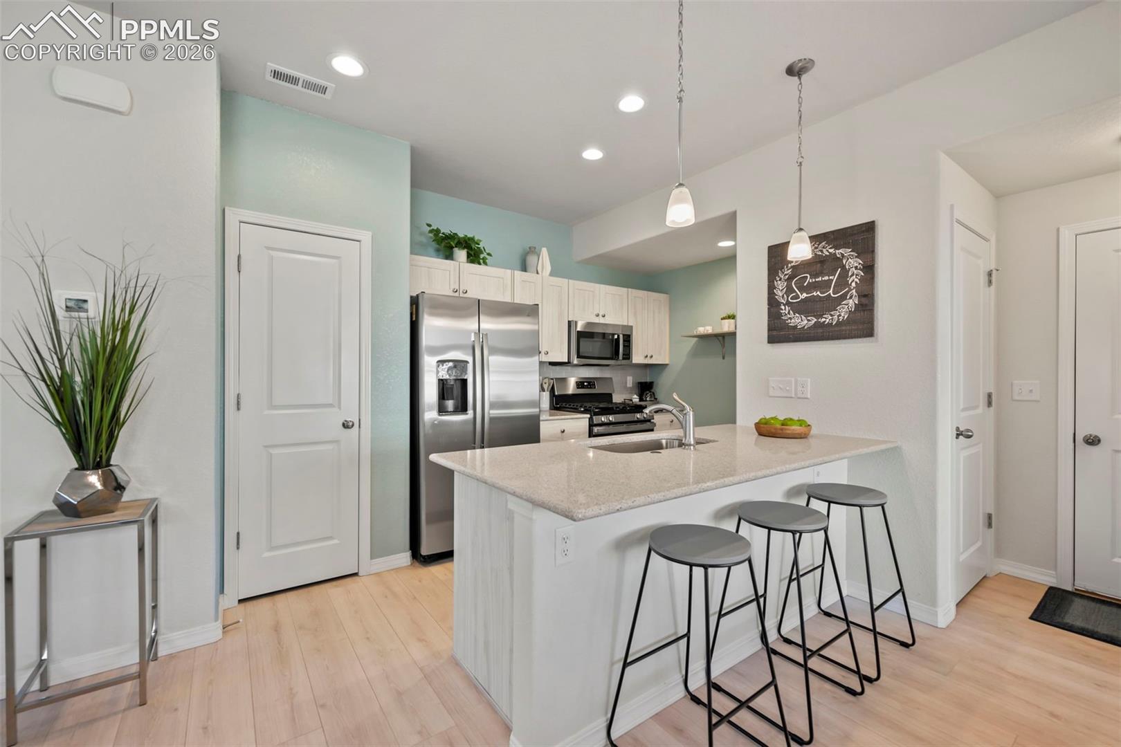 OPEN KITCHEN WITH LARGE ISLAND, STAINLESS STEEL APPLIANCES, QUARTZ COUNTER TOPS, AND PANTRY.