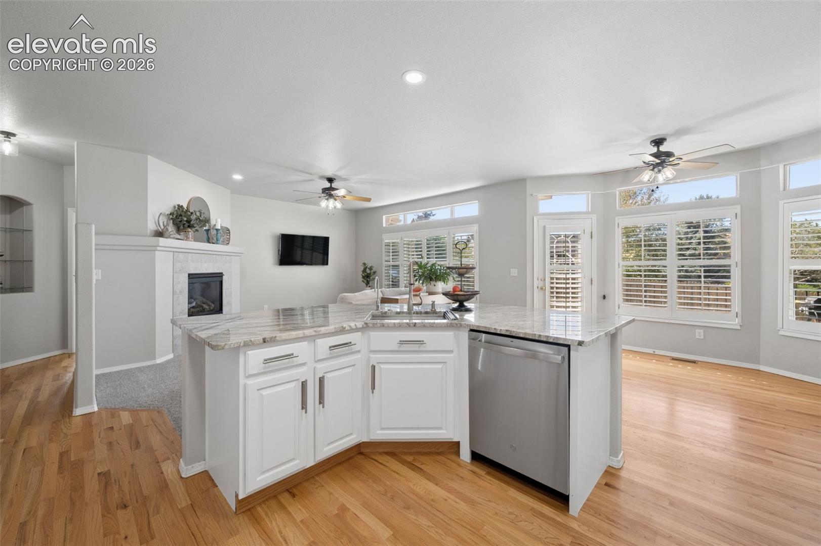 Kitchen island featuring stone countertops, integrated stainless steel dishwasher, and built-in cabinetry
