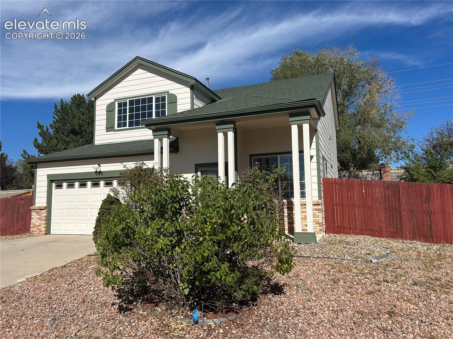 Two-story residence featuring horizontal siding, a covered front porch with decorative columns, gabled rooflines, and an attached two-car garage