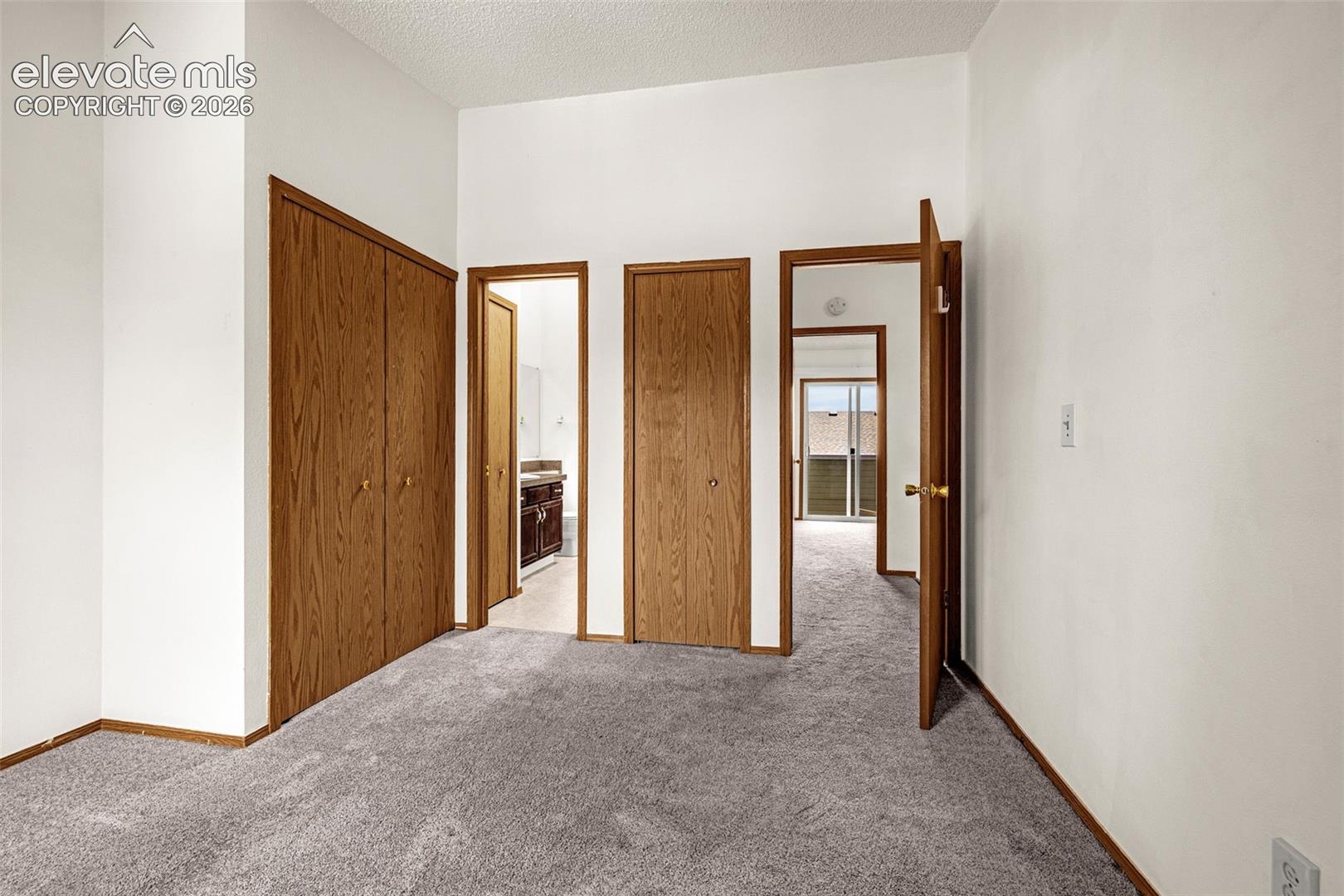 Neutral wall colors, wood-finish doors, and gray carpeting