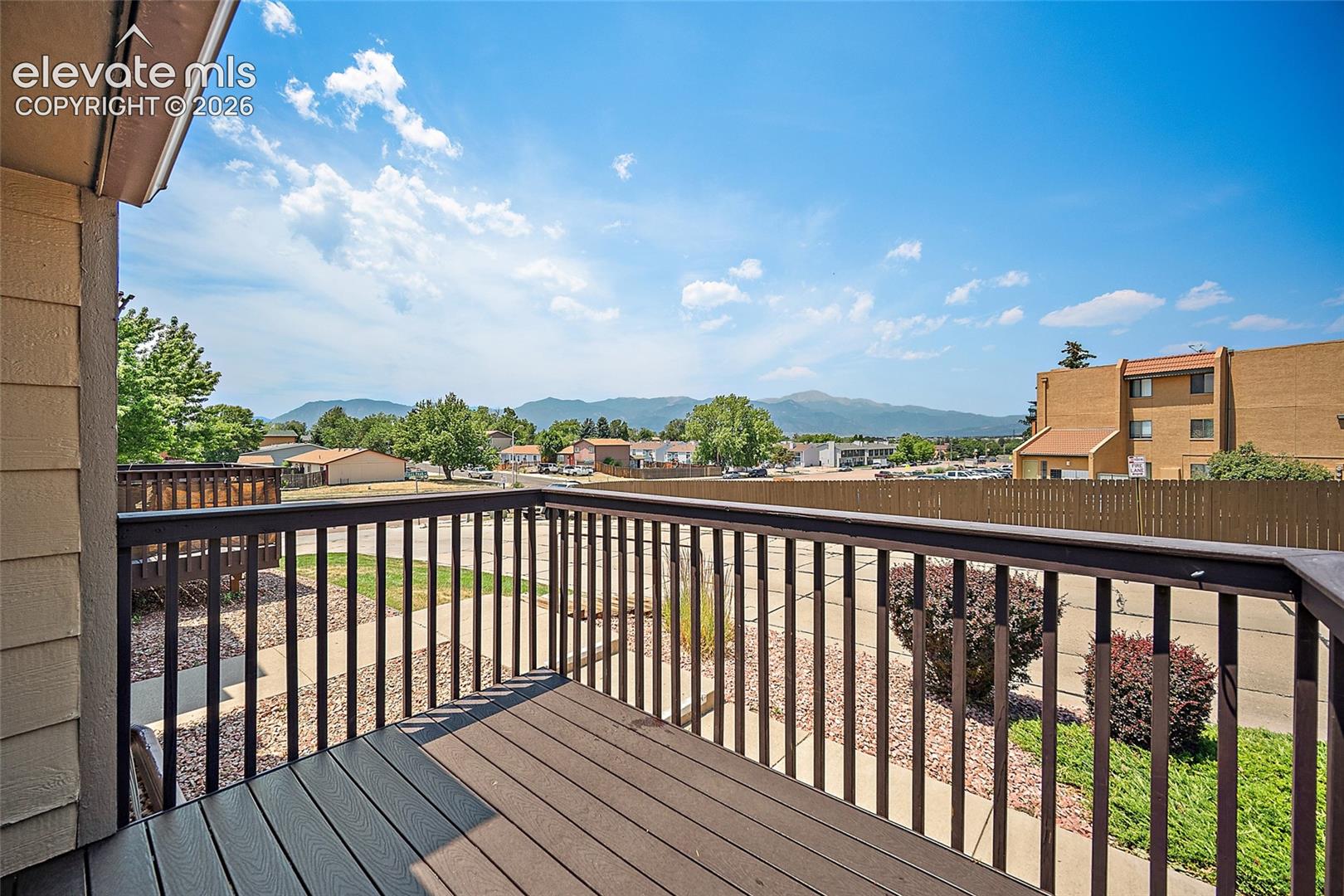 Outdoor balcony featuring composite decking and dark railings, offering mountain and distant building scenery