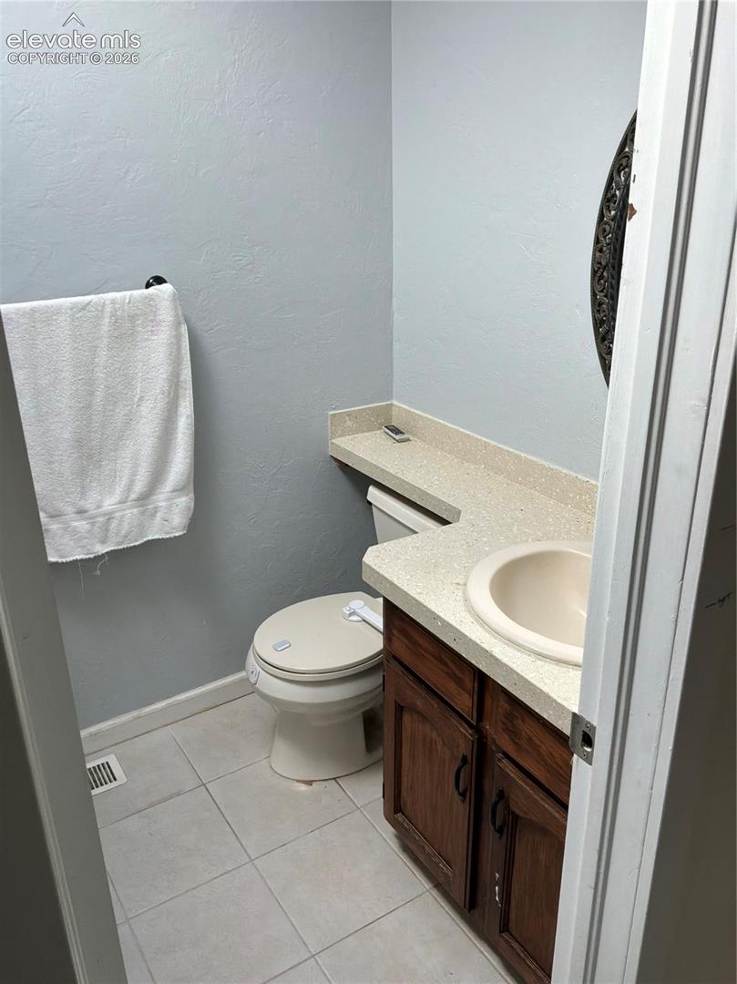 Vanity with a light-colored countertop, integrated sink, and wood-finish cabinetry