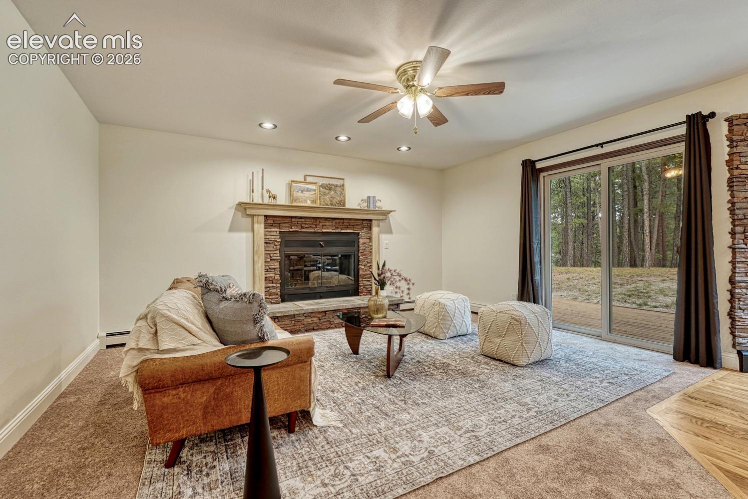 Living area featuring a floor-to-ceiling stone fireplace with a decorative mantel, recessed lighting, a ceiling fan, and sliding glass doors