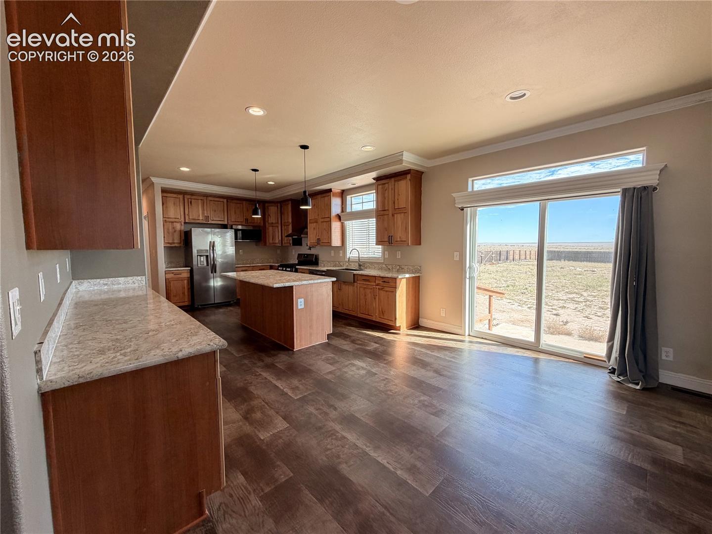 Kitchen featuring stained wood cabinetry, a central island, patterned stone-finish countertops, stainless steel appliances, and wood-finish flooring