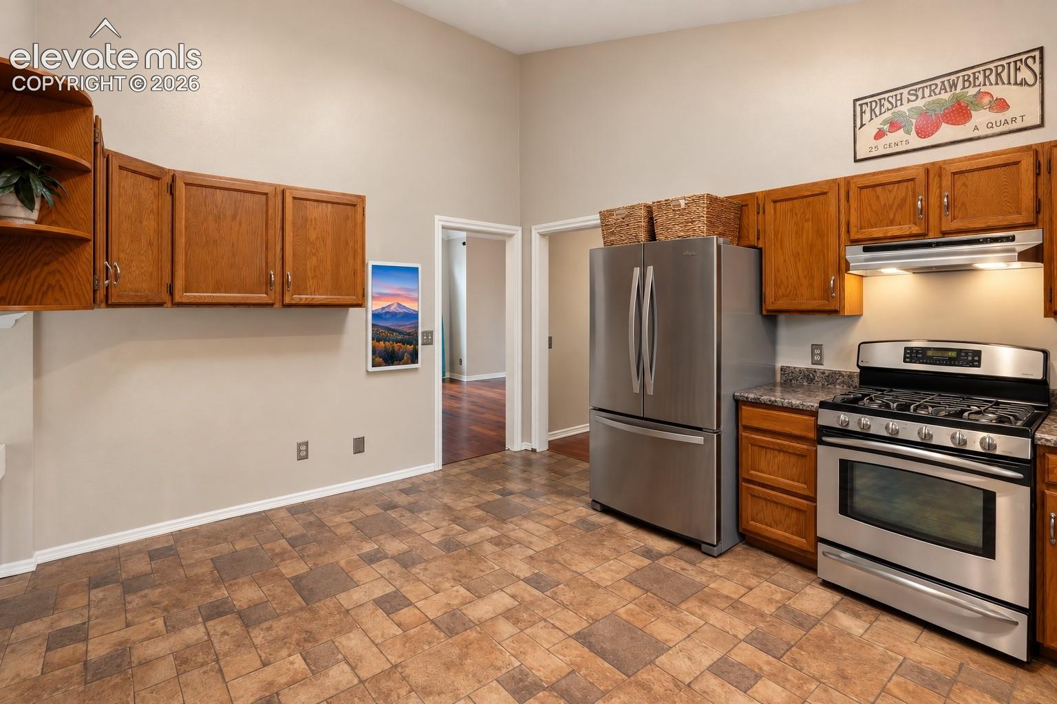 Kitchen featuring warm wood cabinetry, stainless steel appliances, patterned floor tiling, and a built-in oven with gas cooktop